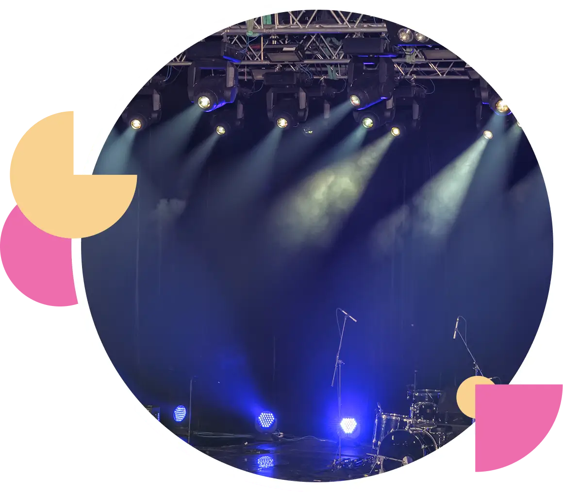 Concert stage with blue and white spotlights illuminating the area.
